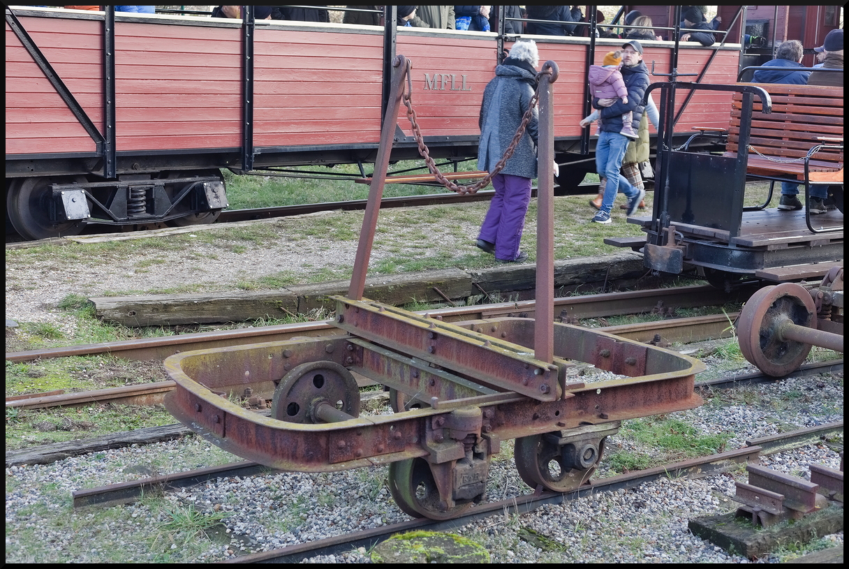 Bei dem kleinem Gefährt handelt es sich um einen sogenannten Waldbahntruck. Zwei Achsen und ein drehbarer Schemel mit den beiden Rungen, war er zum Transport von Holz gedacht. So wurde er auch ursprünglich an das Sägewerk Nossen vom Hersteller Kelle & Hildebrand Dresden im Jahr 1900 geliefert. Die Lore kam dann 1999 zur Museumsfeldbahn Leipzig-Lindenau und ist dort ein Ausstellungsstück.